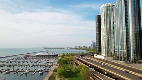 Cars-Passing-Water-Front-Modern-Luxurious-Buildings-Drone-In-Chicago