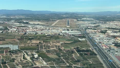 Real-time-approach-to-land-at-Valencia-airport,-Spain,-shot-from-an-airplane-cabin,-while-other-airplane-is-taking-off