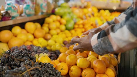 Nahaufnahme-Eines-Mannes-Mit-Schwarzer-Haut-In-Einem-Karierten-Wollhemd-Mit-Prall-Gefüllten-Mandarinen-Auf-Einer-Breiten-Theke-In-Einem-Supermarkt