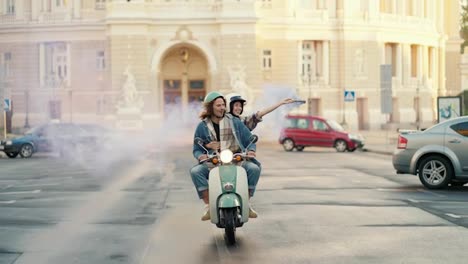 A-happy-guy-with-curly-long-hair-in-a-denim-shirt-and-pants-rides-a-green-moped-with-his-girlfriend-who-is-holding-a-blue-fire-in-her-hands-that-produces-smoke-and-leaves-behind-a-blue-trail-on-a-wide-street-in-the-morning-in-the-city