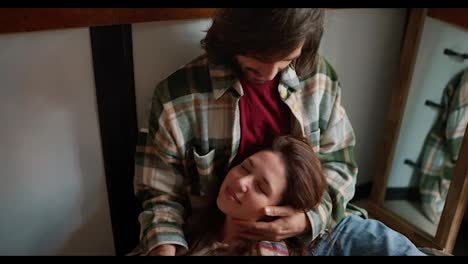 A-happy-brunette-girl-in-a-checkered-shirt-lies-on-the-lap-of-her-brunette-boyfriend-in-a-green-checkered-shirt,-and-he-strokes-her-during-their-communication-in-a-trailer-during-a-picnic-outside-the-city-in-the-summer