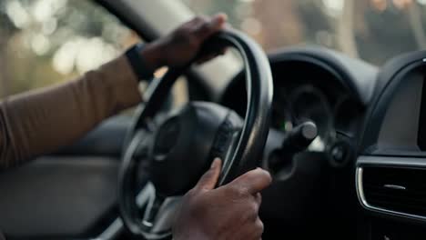 Close-up-of-the-hands-of-a-confident-male-businessman-with-Black-skin-color-that-he-holds-on-the-steering-wheel-during-his-business-trip-in-a-modern-car-in-the-city