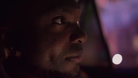 Close-up-a-man-with-Black-skin-and-a-beard-rides-through-the-evening-city-in-the-interior-of-a-modern-car-looks-and-enjoys-the-views-during-his-trip