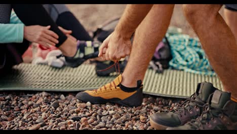 Close-up-shot-of-a-man-putting-on-special-climbing-shoes-as-he-prepares-to-climb-on-a-rocky-seashore.-Man-Rock-puts-on-special-shoes-and-sneakers-to-start-pounding-the-rock