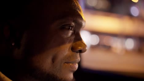 Close-up-a-confident-man-with-Black-skin-a-short-haircut-and-a-beard-rides-in-a-modern-car-interior-through-the-evening-city-during-his-business-trip