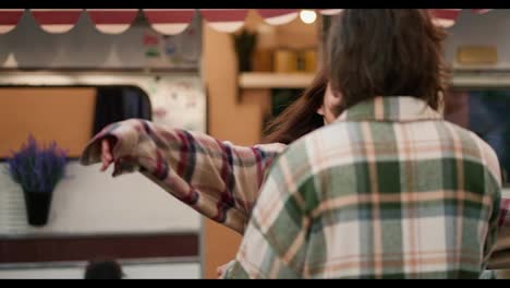 A-happy-brunette-girl-in-a-plaid-shirt-jumps-into-the-arms-of-her-brunette-boyfriend-in-a-green-plaid-shirt-and-hugs-him-during-their-vacation-in-a-camp-near-a-trailer-outside-the-city-in-the-summer