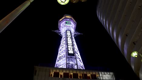 Looking-Up-At-Tsutenkaku-Tower-Illuminated-At-Night-In-Shinsekai-District-Of-Osaka