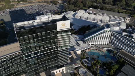 Aerial-top-down-shot-of-luxury-Crown-Casino-Hotel-in-Perth-City-lighting-in-sunset-and-parking-cars-in-backdrop