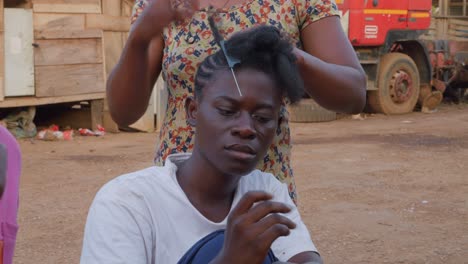 African-woman-braiding-her-hair-in-Kumasi,-Ghana