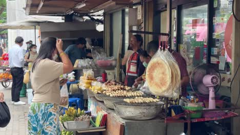 Street-food-vendors-selling-and-packing-food-for-customers-in-Yaowarat-Chinatown,-Bangkok,-Thailand