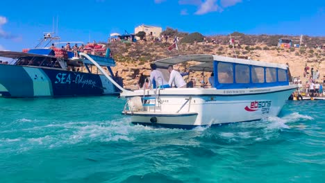 Ebsons-Comino-Ferries-sailing-near-the-moored-Sea-Odyssey-boat-in-the-Blue-Lagoon-Bay-in-Malta