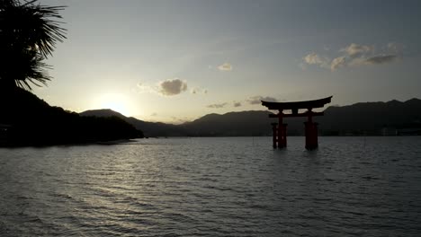 Rama-De-Pino-Moviéndose-Con-Vista-De-Silueta-De-La-Puerta-Flotante-Grand-Torii-Durante-La-Puesta-De-Sol-En-El-Fondo-En-Itsukushima