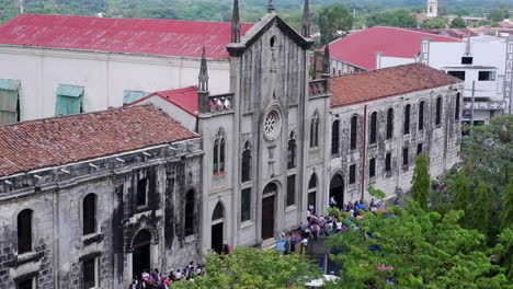 Pigeons-swoop-thru-plaza-in-front-of-Asuncion-School-facade,-Leon,-NIC