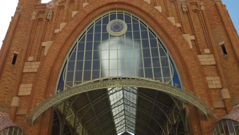 Vertical-traveling-view-of-the-facade-of-the-Colon-Market-in-Valencia-on-a-sunny-day,-Spain