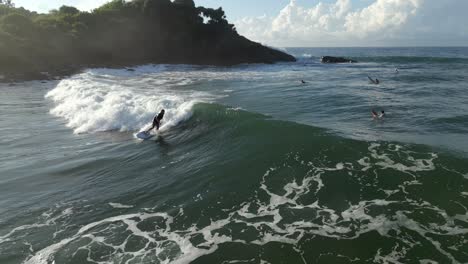 Aerial-Drone-Shot-of-Caucasian-Male-Surfer-Catching-a-Wave-and-Surfing-Towards-the-Camera-in-Tropical-Southern-Sri-Lanka-on-Sunny-Morning