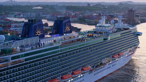 Aerial-dolly-along-cruise-ship-docked-in-historic-Caribbean-port-at-blue-hour