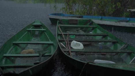 Floating-green-canoe-boats-slowly-filling-up-in-heavy-tropical-rain-on-Brazil's-black-river
