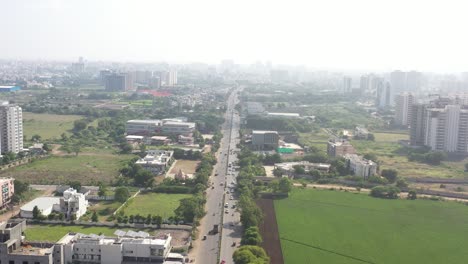 Die-Drohne-Aus-Der-Luftaufnahme-Der-Stadt-Rajkot-Fliegt-Mitten-Auf-Der-Kalavad-Straße.-Am-Straßenrand-Ist-Auch-Ein-Tempel-Zu-Sehen