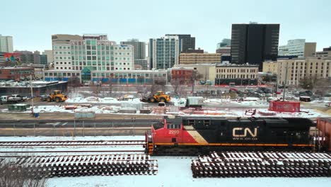 4k-Estático-Lapso-De-Tiempo-Disparo-De-Drone-Colorido-Acero-Transportar-Industrial-Cn-Carril-Industrial-Tren-Vapor-Carbón-Locomotora-Conduciendo-Por-El-Centro-Invierno-Urbano-Winnipeg-Manitoba-Canadá