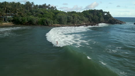 Toma-Aérea-De-Un-Drone-De-Una-Surfista-Caucásica-Atrapando-Y-Montando-Una-Ola-Y-Cayendo-En-El-Sur-De-Sri-Lanka