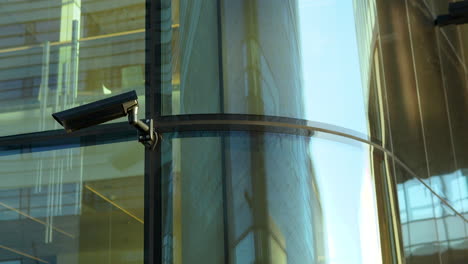 Security-camera-mounted-on-reflective-glass-building