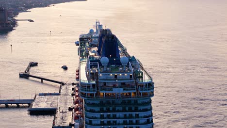 High-angle-aerial-orbit-around-top-of-cruise-ship-in-port-town-of-the-Caribbean
