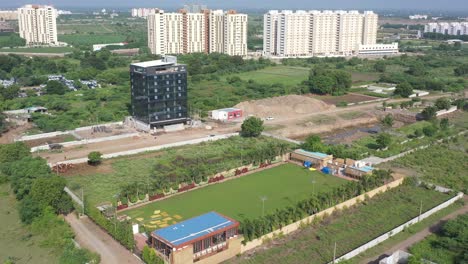 Cámara-De-Vista-Aérea-De-La-Ciudad-De-Rajkot-Moviéndose-Desde-Arriba-De-La-Parcela-Del-Partido-Hacia-Un-Edificio-De-Gran-Altura-En-Construcción