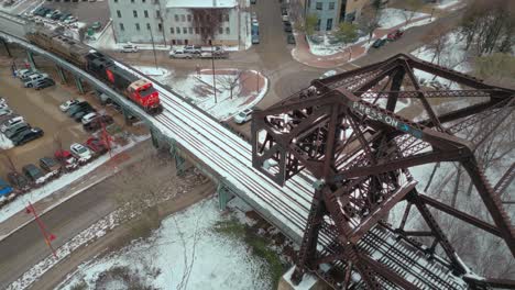 Un-Clip-Aéreo-De-Drones-De-4k-De-Ancho-De-Una-Gran-Locomotora-De-Tren-Cn-De-Transporte-De-Energía-De-Carbón-Industrial-Conduciendo-Por-Vías-A-Través-Del-Puente-De-Cruce-De-Río-De-Acero-En-Invierno-Winnipeg-Manitoba-Canadá