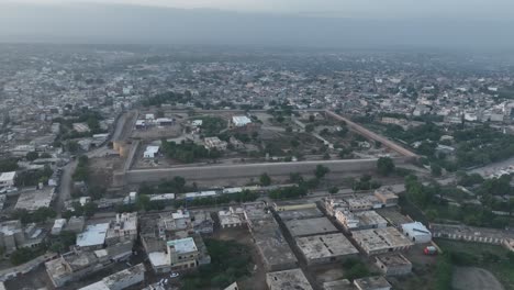 Aerial-drone-rotating-shot-over-the-city-of-Umerkot-in-Tharparkar,-Pakistan-on-a-cloudy-evening