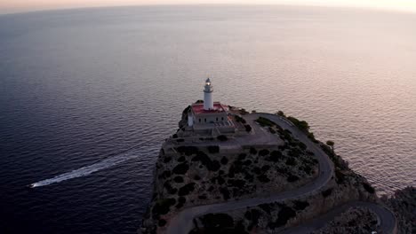 Historic-old-lighthouse-on-the-edge-of-cliff-overlooking-the-sea-in-light-of-the-setting-sun,-timelapse-color-change-to-night,-aerial-drone