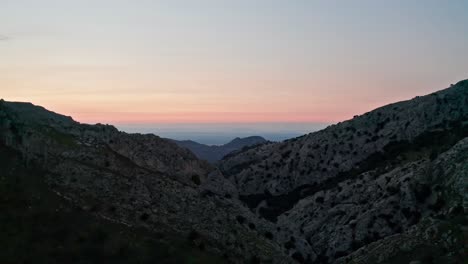 Sonnenuntergang-Zwischen-Klippen-Einer-Berglandschaft-Mit-Dem-Meer-Im-Fernen-Hintergrund