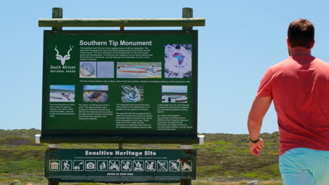 Mann-Geht-Auf-Die-Informationstafel-Des-Southern-Tip-Monument,-Cape-L&#39;Agulhas,-Zu