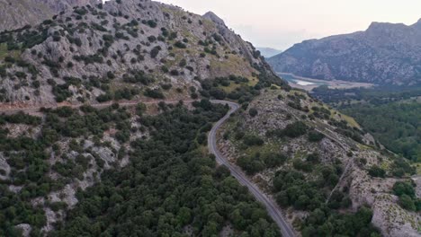 Winding-Mountain-Pass-Road-Through-Green-Rocky-Landscape,-aerial-drone