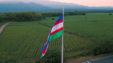 -Orbital-aerial-view-zooming-in-on-the-large-Cali-flag-at-the-southern-entrance-of-the-city,-Valle-del-Cauca,-Colombia