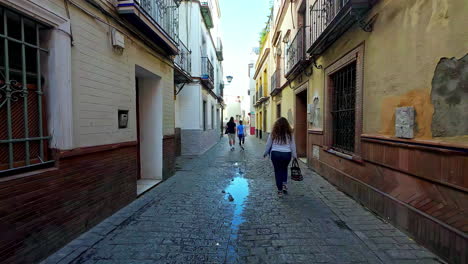 Seville,-Andalusia-houses-and-stone-paved-street-with-people-walking,-Spain