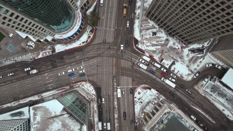 Long-Rising-Drone-Overhead-Vehicle-Traffic-4K-Time-lapse-Winter-Wide-Shot-Canadian-Roadway-Trans-Highway-One-Intersection-Portage-Avenue-and-Main-Street-Capital-City-Downtown-Winnipeg-Manitoba-Canada