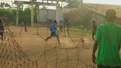 Boys-dribbling-and-passing-the-ball-through-defenders-making-dust-from-the-dry-ground-at-a-community-football-field,-Kumasi,-Ghana