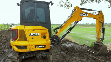 Drivers-operating-heavy-equipment-for-excavating-and-compacting-a-piece-of-land-for-construction-in-an-agricultural-area-in-Chachoengsao-province,-Thailand