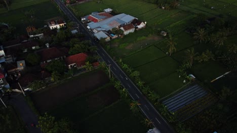 Vista-Aérea-Sobre-El-Hermoso-Pueblo-De-Amed-Con-Vista-A-Una-Carretera-Muy-Transitada,-Coloridos-Edificios-Históricos-Y-Vegetación-Mientras-Viaja-Por-Bali-En-Indonesia