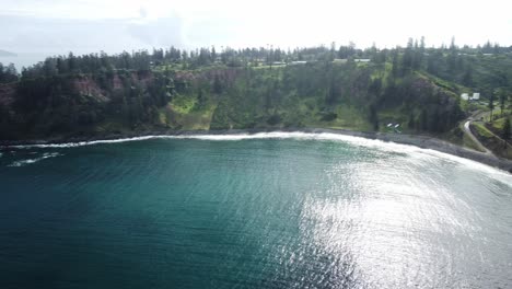 Aerial-view-of-the-picturesque-landscape-in-norfolk-island-with-a-view-of-the-turquoise-sea-water-with-foaming-waves-breaking-on-the-rocky-cliffs-and-vegetation-of-forests-and-bushes