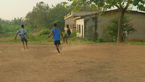 Ein-Junger-Mann-Gibt-Den-Ball-Einem-Teamkollegen-Zu-Und-Passt-Dann-Zurück,-Während-Man-Ihn-Beim-Fußballspielen-Auf-Einem-Staubigen-Gemeinschaftsfußballfeld-In-Kumasi,-Ghana,-Sieht