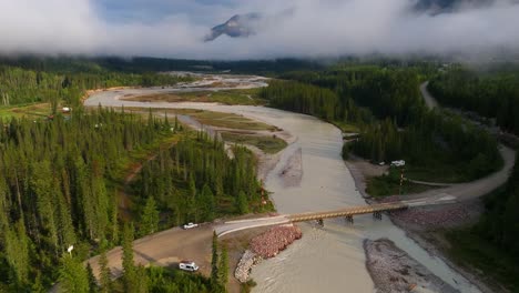 Drone-shot-pushing-forward-and-tilting-up-to-reveal-mountains-with-low-hanging-clouds-over-the-Kicking-Horse-River-in-British-Columbia-Canada