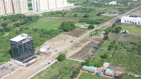 RAJKOT-CITY-AERIAL-VIEW-DAWN-CAMERA-FLYING-OVER-PARTY-PLOT-FROM-SIDE-ANGLE,-SEVERAL-FOURWHEEL-PARKED-BEHIND-BUILDING