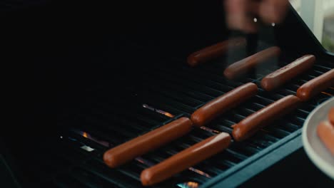 Placing-hotdogs-on-grill-with-metal-tongs