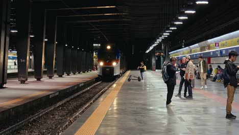 A-train-arriving-at-a-subway-station-in-Naples,-Italy-with-passengers-waiting-and-disembarking