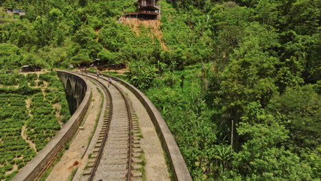 Ella-Sri-Lanka-Aerial-v31-drone-flyover-Nine-Arches-Bridge-capturing-tourists-walking-along-the-railway-track-amidst-the-lush-valley-and-jungle-vegetation---Shot-with-Mavic-3-Cine---April-2023