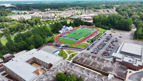 Aerial-cinematic-shot-of-football-stadium-and-car-park-in-high-school-complex
