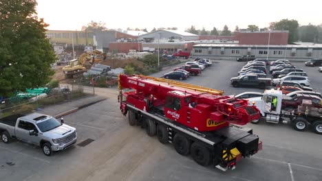Construction-site-at-a-school-in-small-town-America,-featuring-a-red-crane-and-parked-cars