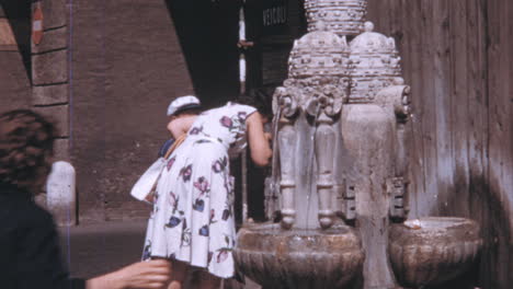 Frau-Mit-Ihrem-Sohn-Trinkt-Wasser-Aus-Der-Fontana-Delle-Tiare-In-Rom-Der-1960er-Jahre