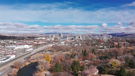 Drone-aerial-view-flying-towards-Reno,-Nevada-over-the-river-and-highway